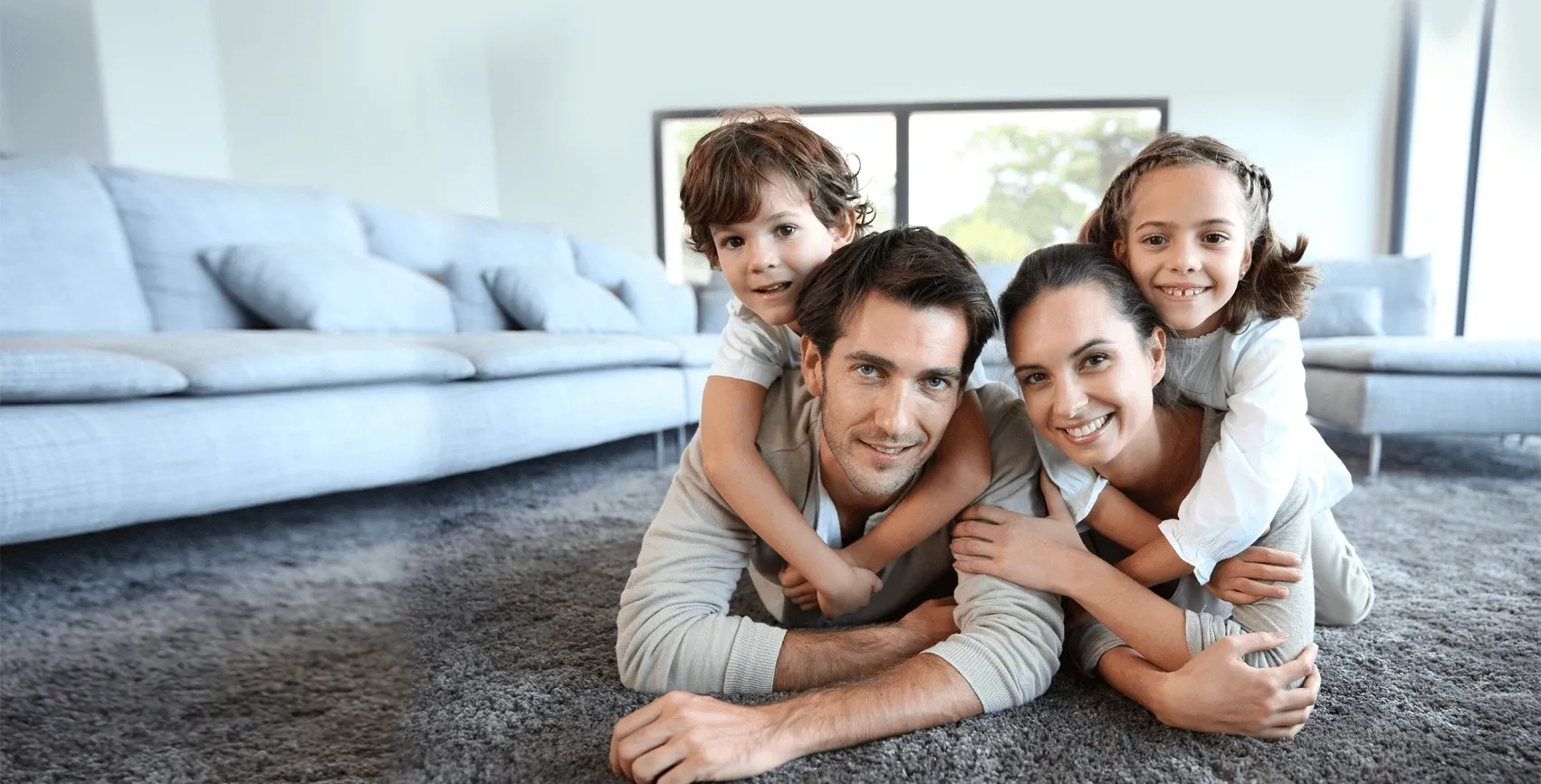 A family laying on the floor in front of a couch.